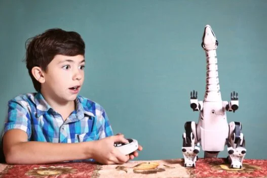 Dreng der leger med fjernstyret dinosaur