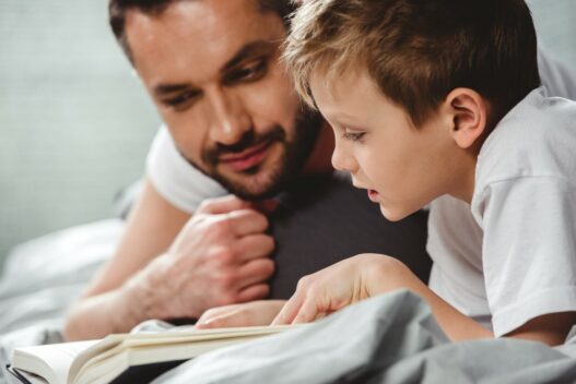 Far og søn der læser i en dinosaur bog